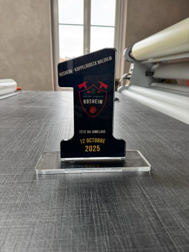 Trophée en forme de numéro un, noir avec un logo en rouge et une base transparente.